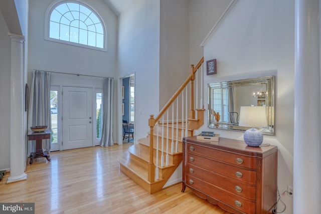 entryway with plenty of natural light, decorative columns, a high ceiling, and light wood-type flooring