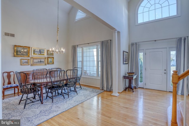 dining area with decorative columns, a chandelier, and light hardwood / wood-style floors