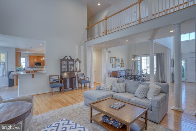 living room with a wealth of natural light, light hardwood / wood-style floors, and ornate columns