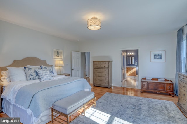 bedroom featuring connected bathroom and light hardwood / wood-style flooring