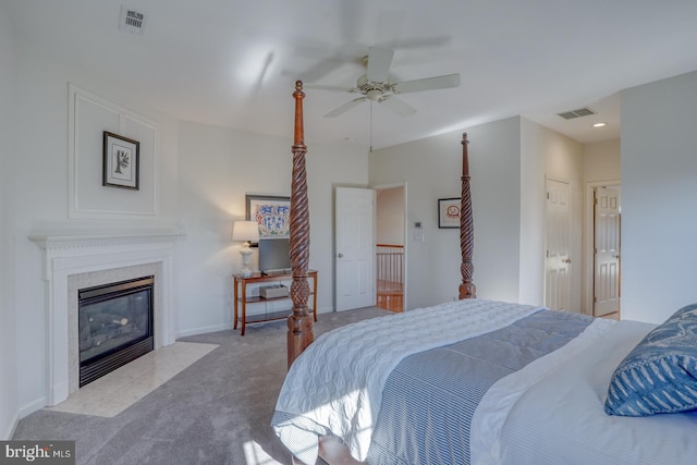 bedroom featuring light carpet, a fireplace, and ceiling fan