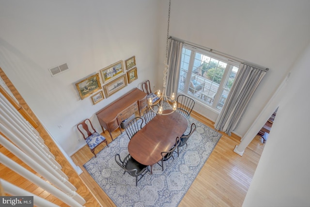 dining room with hardwood / wood-style floors, a towering ceiling, and a chandelier