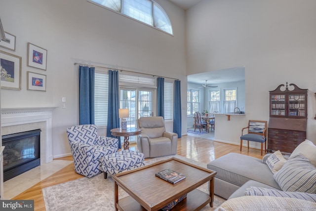 living room with a towering ceiling, light hardwood / wood-style floors, and a premium fireplace