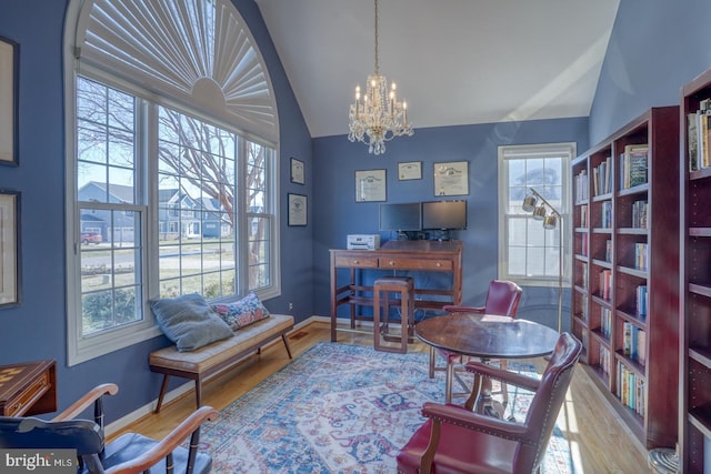 office area featuring vaulted ceiling, light wood-type flooring, and an inviting chandelier