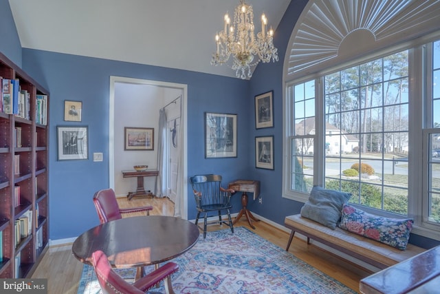 living area featuring hardwood / wood-style flooring, vaulted ceiling, and a chandelier