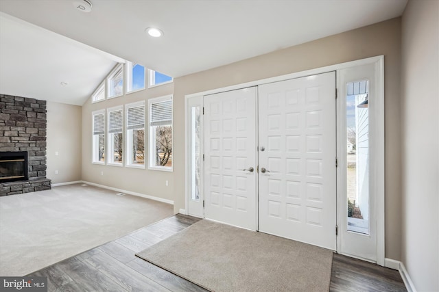 entryway with vaulted ceiling, dark wood-type flooring, and a fireplace