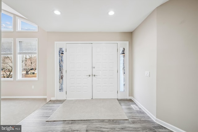 foyer featuring wood-type flooring and vaulted ceiling