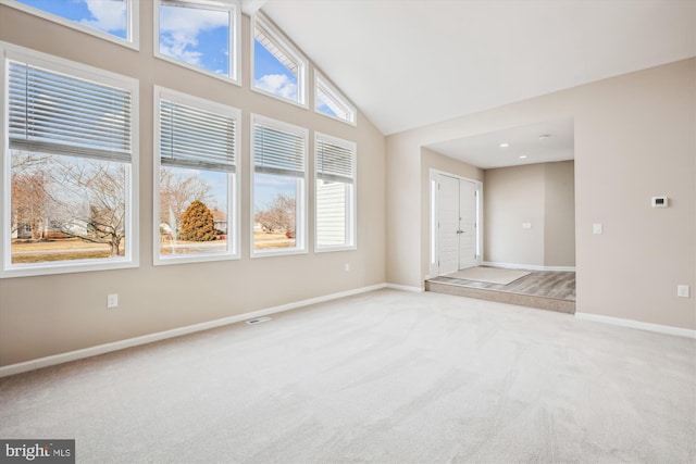 carpeted empty room featuring high vaulted ceiling