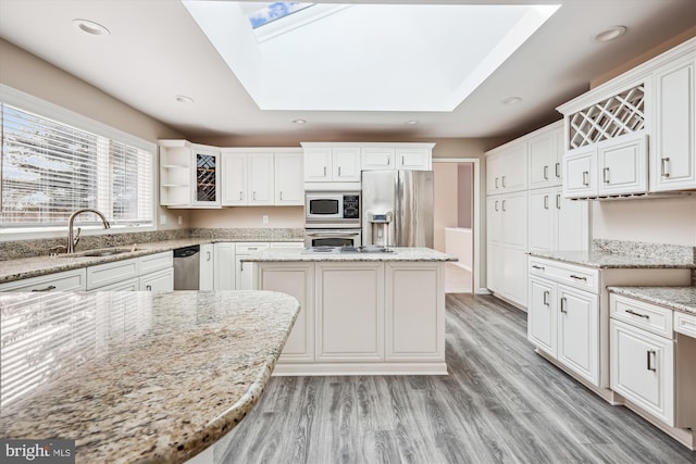 kitchen with light stone counters, stainless steel appliances, sink, and a kitchen island