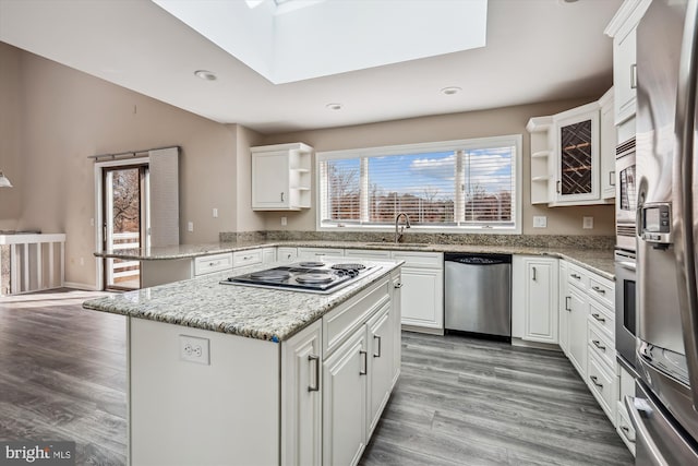 kitchen with sink, light stone counters, white cabinetry, a kitchen island, and stainless steel appliances