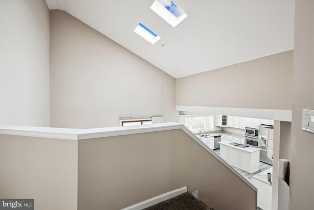 stairway with vaulted ceiling with skylight and sink