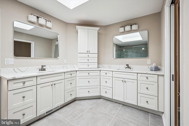 bathroom with tile patterned flooring, vanity, walk in shower, and a skylight