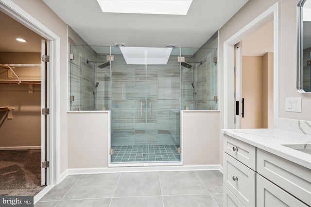 bathroom featuring a skylight, vanity, tile patterned flooring, and a shower with shower door