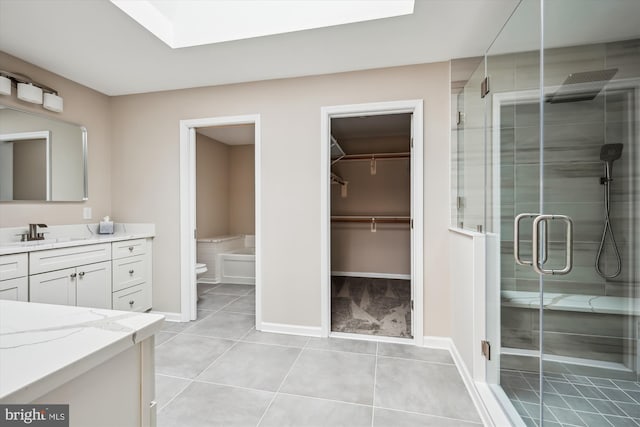 bathroom featuring walk in shower, tile patterned floors, toilet, a skylight, and vanity