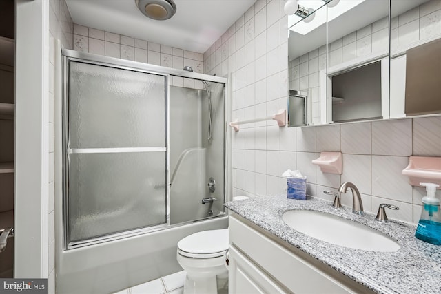 full bathroom with toilet, tile walls, vanity, enclosed tub / shower combo, and backsplash