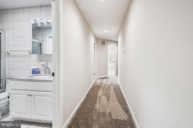 hall featuring sink and light colored carpet