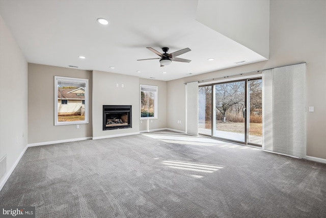 unfurnished living room featuring carpet floors, a wealth of natural light, and ceiling fan