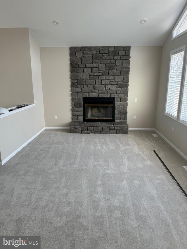 unfurnished living room featuring lofted ceiling, light carpet, and a fireplace