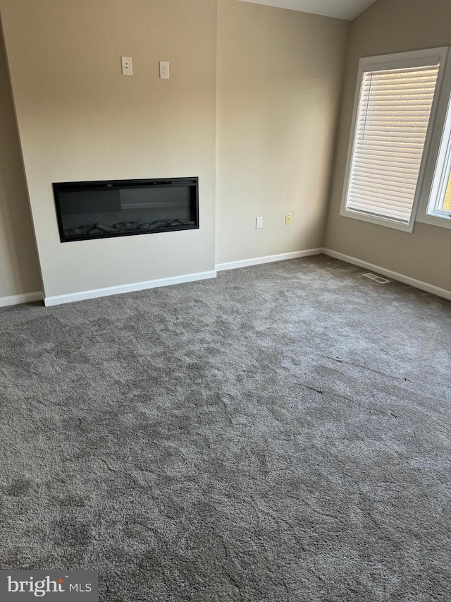 unfurnished living room with dark colored carpet