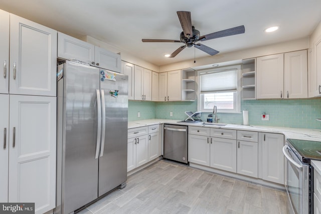 kitchen with sink, white cabinetry, backsplash, stainless steel appliances, and light wood-type flooring