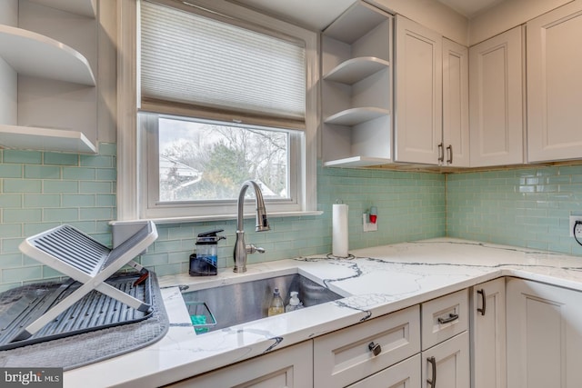 kitchen featuring white cabinetry, light stone countertops, sink, and decorative backsplash