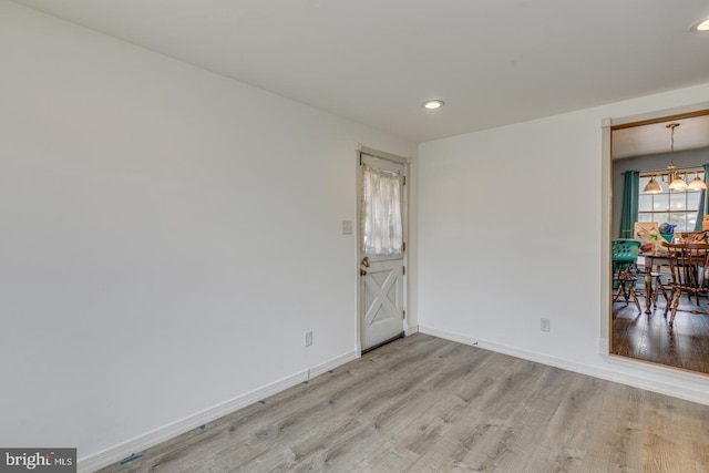 empty room with light hardwood / wood-style flooring and a notable chandelier