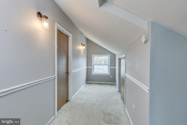 hallway with light colored carpet and vaulted ceiling