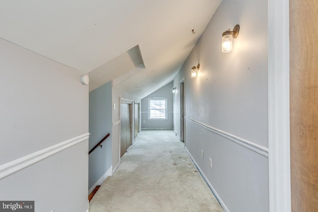 hallway with vaulted ceiling and light colored carpet