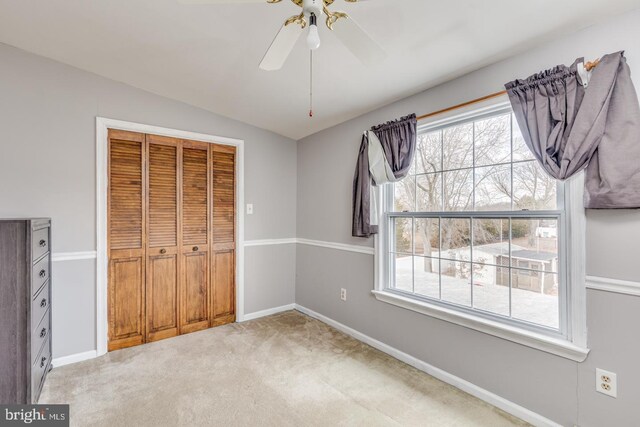 unfurnished bedroom featuring vaulted ceiling, carpet, ceiling fan, and a closet