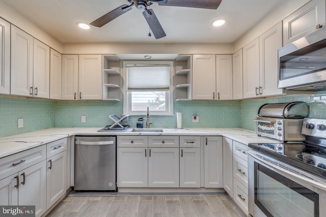 kitchen featuring sink, light stone counters, tasteful backsplash, appliances with stainless steel finishes, and white cabinets