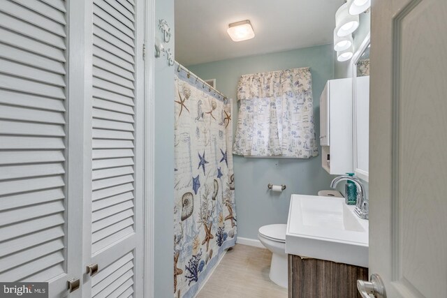 bathroom with walk in shower, vanity, and toilet