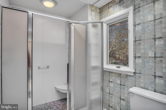 bathroom with toilet, a shower with door, and tile walls