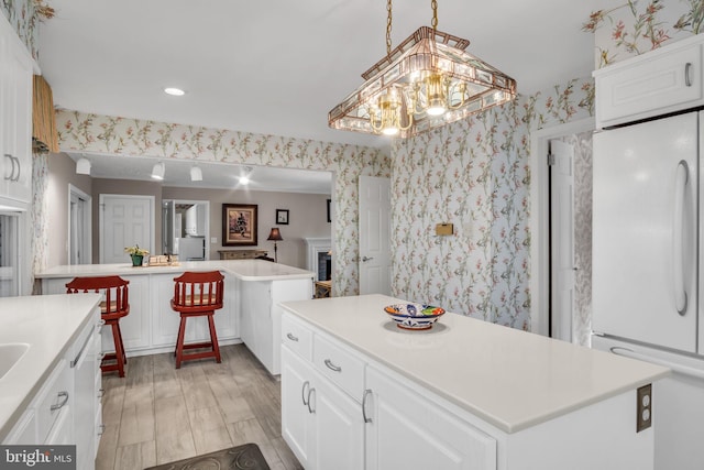 kitchen with a kitchen island, white fridge, and white cabinets