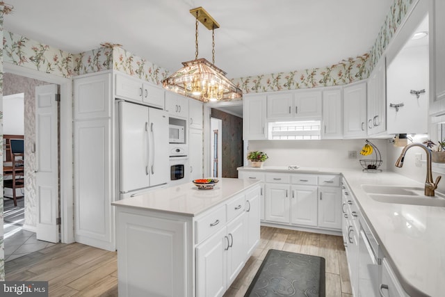 kitchen featuring sink, white cabinets, hanging light fixtures, a center island, and white appliances