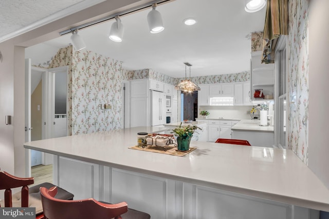 kitchen featuring a kitchen bar, white cabinetry, decorative light fixtures, white refrigerator, and light hardwood / wood-style floors