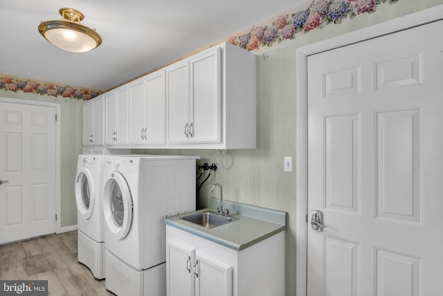 washroom with cabinets, washing machine and dryer, sink, and light hardwood / wood-style flooring