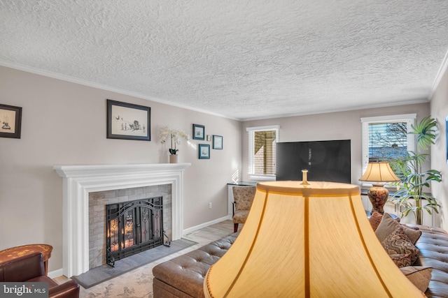 living room with ornamental molding, light hardwood / wood-style floors, a tile fireplace, and a textured ceiling