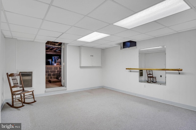 basement featuring a paneled ceiling and heating unit