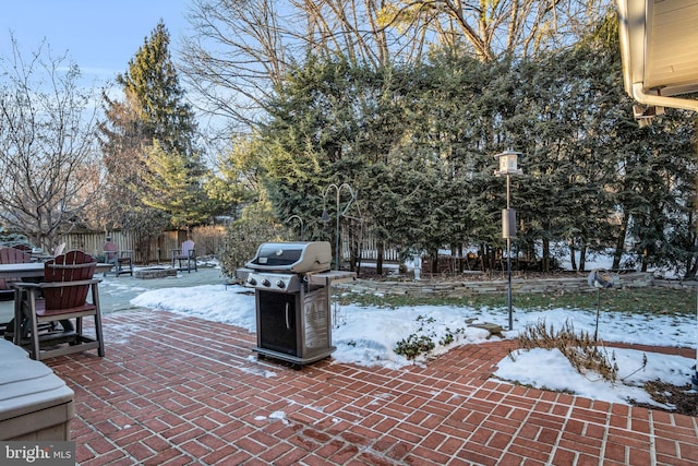 snow covered patio with an outdoor fire pit