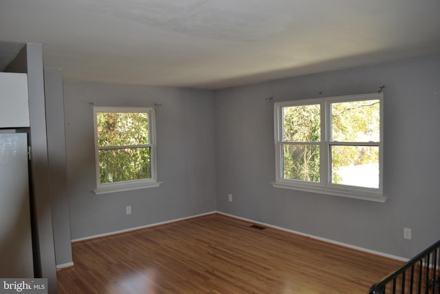 unfurnished bedroom with wood-type flooring and stainless steel refrigerator