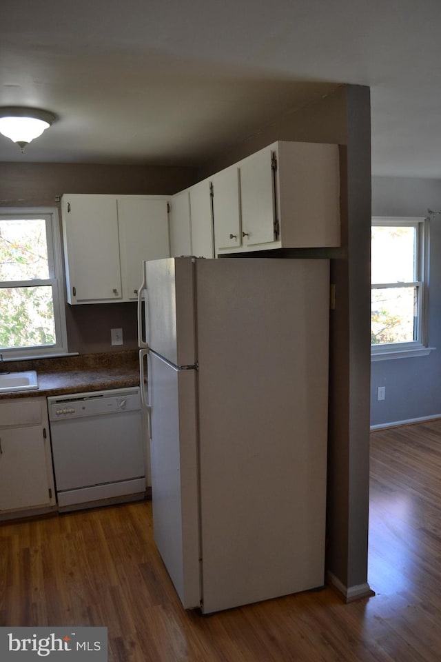 kitchen with white appliances, plenty of natural light, hardwood / wood-style floors, and white cabinets