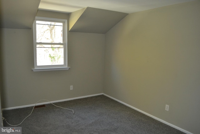 bonus room with dark carpet and vaulted ceiling