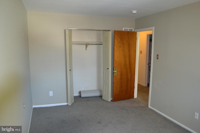 unfurnished bedroom with light colored carpet and a closet