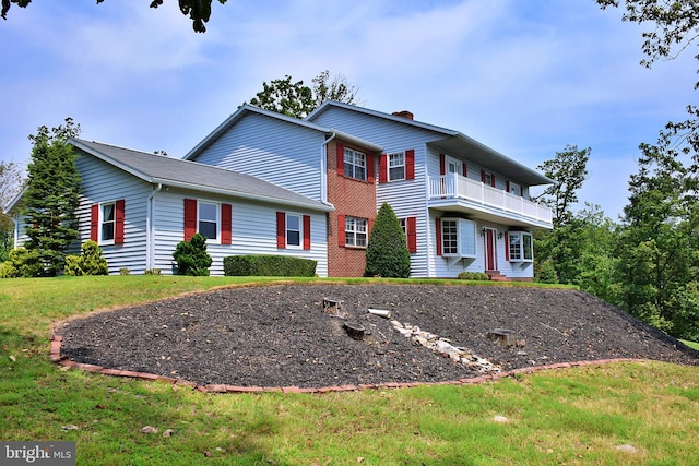 view of front facade with a balcony and a front yard