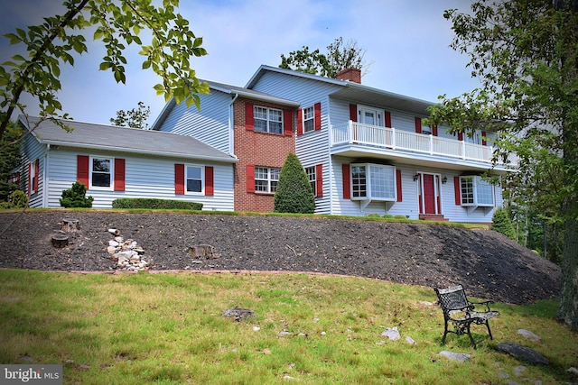 view of front of house with a front yard and a balcony