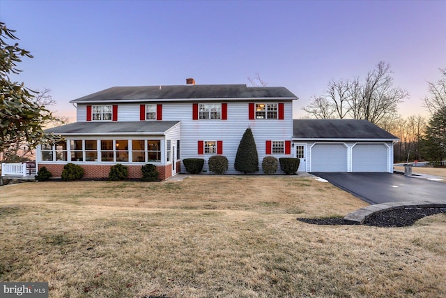 view of front of property with a garage, a sunroom, and a yard