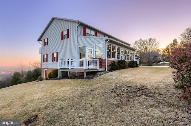 exterior space with a wooden deck, a sunroom, and a lawn