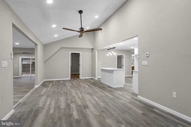 unfurnished living room with hardwood / wood-style flooring, high vaulted ceiling, and ceiling fan