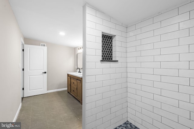 bathroom with vanity, a tile shower, and tile patterned floors