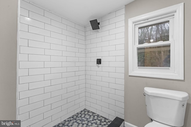 bathroom featuring tiled shower and toilet